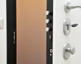 Detalle de una puerta de seguridad con varios tipos de cerraduras y un cerrojo con llave.
