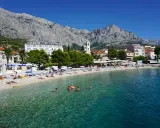 Słoneczna plaża w Baška Voda, z turkusową wodą i górami w tle. To idealne miejsce na relaks i odkrywanie atrakcji.