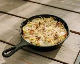 Gratin dauphinois, une spécialité Auvergne, doré et gratiné dans sa poêle en fonte sur une table en bois.