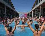 Folla entusiasta partecipa a una lezione di acquagym all'aperto, con le braccia alzate, durante la fiera dello sport Rimini.