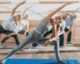 Menschen unterschiedlichen Alters üben Yoga. Sanfte Bewegungen wie diese sind ideal für Gymnastik bei Osteoporose, um Kraft und Gleichgewicht zu fördern.