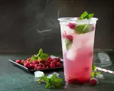 En uppfriskande raspberry daiquiri med färska hallon och mynta, serverad i ett plastglas med is.