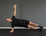 Uomo in posizione di side plank, con un braccio sollevato e l'altro appoggiato a terra.