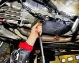 Mechanik wykonuje wymianę oleju w skrzyni automatycznej, używając specjalistycznego sprzętu do serwisu.
