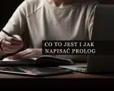 Osoba pisze piórem w notatniku, obok leży tablet i laptop. Tekst na ekranie: "Co to jest i jak napisać prolog".