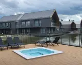 Relaks przy jacuzzi i basenie z widokiem na nowoczesne domki nad wodą. Idealne miejsce na wypoczynek w stylu termy Karkonosze.