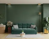Un acogedor salón con un sofá verde, plantas y una lámpara dorada.