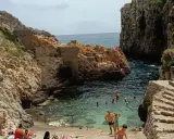 Santa Maria di Leuca: cosa vedere? Una caletta rocciosa con gente che nuota e si rilassa, con scalinate di pietra che scendono verso il mare cristallino.