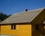 Żółty domek z widocznym pełnym deskowaniem dachu, przygotowanym pod pokrycie.
