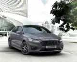 Ford Mondeo gris aparcado frente a un edificio moderno. Las medidas del Ford Mondeo son ideales para la ciudad.