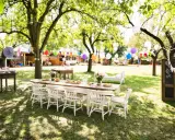 Une table dressée pour un repas en plein air, avec des guirlandes et des ballons, évoque une ambiance de deco jardin boheme chic.