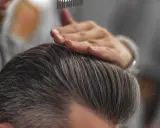 Stylista układa włosy, pokazując, jak mieć gęste włosy chłopak.