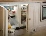 Un frigorifero integrato, quasi invisibile, con ante in legno che si fondono con l'arredamento, perfetto per nascondere il frigorifero in soggiorno.
