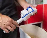 Ręce trzymają mechanizm spłuczki, przygotowując go do odkamieniania.