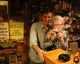 Au café du coin Le Mans, Jeanine, 73 ans, fan de rockeur, allume sa pipe. Un homme souriant se tient à ses côtés.