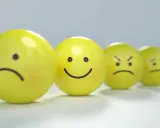 Rząd żółtych kulek z różnymi minami, od smutnej po wściekłą, odzwierciedla nadwydajność mentalną i jej skutki.