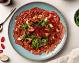 Rindercarpaccio mit Pilzen, Rucola und Mandeln. Eine köstliche Variation von Carpaccio, garniert mit Chili und Trüffel.