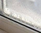 Ventana con gotas de agua, un claro ejemplo de condensación. El vapor de agua se ha adherido al cristal, formando pequeñas gotas que resbalan por el marco.
