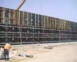 Trabajador supervisa el encofrar muro de gran tamaño, con estructura metálica y paneles negros, listo para el hormigón.