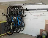 Système de rangement astucieux pour vélos dans un garage, plusieurs vélos suspendus au plafond pour optimiser l'espace.
