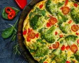 Pyszny omlet na słono z brokułami, pomidorkami i papryką, podany w patelni.