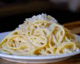 Pyszne cacio e pepe, czyli spaghetti z serem i pieprzem, posypane startym parmezanem.