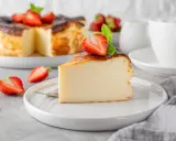 Kawałek pysznego sernika proteinowego z truskawkami i miętą na talerzu.