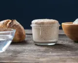 Un bocal de levain actif, du pain, de l'eau et de la farine illustrent la différence entre levain et levure.