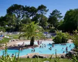 Disfruta de un día soleado en el camping de País Vasco, con una piscina refrescante y gente relajándose en tumbonas.