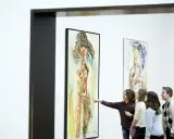 A group of children admire a painting in the style of the cobra art movement, with one girl pointing at the abstract figure.