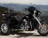 Harley-Davidson negro de tres ruedas aparcado en un paisaje montañoso. Recuerda que las motos de tres ruedas necesitan carnet de moto.