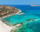Rajska plaża z turkusową wodą, statkami i ludźmi. Kreta wschodnia atrakcje zachwycają!