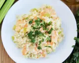 Pyszne risotto z krewetkami, udekorowane natką pietruszki, obok łodygi selera i oliwy.