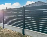Nowoczesne ogrodzenie z poziomych paneli, osadzone na betonowym cokole. To świetne rozwiązanie co zamiast podmurówki pod ogrodzenie, zapewniające estetykę i trwałość.