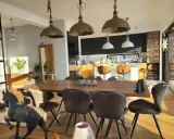 Oświetlenie salonu inspiracje: industrialne lampy wiszące nad drewnianym stołem, nowoczesna kuchnia w tle.