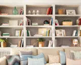 Estanterías blancas llenas de libros, plantas y objetos decorativos. Una idea de **qué poner detrás del sofá** para crear un rincón acogedor y lleno de estilo.