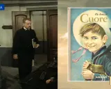 Un uomo in abito scuro tiene un libro, forse un riassunto di tutti i capitoli del libro Cuore di De Amicis, la cui copertina è visibile a destra.