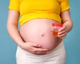 Ciężarna kobieta trzyma pojemnik z próbką moczu, badanie na obecność ketonów w moczu w ciąży.