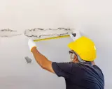 Inspektor mierzy plamy pleśni na suficie w łazience, które przypominają grzyby.
