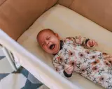Bebé llorando en su cuna, con un pijama de koalas. Un momento difícil para dejar llorar a un niño de 2 años para dormir.