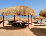 Słoneczna plaża z leżakami i parasolami z trawy. Idealne miejsce na relaks w stylu caves beach resort.