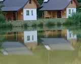 Urokliwe łowisko z domkami letniskowymi, których odbicia tańczą na spokojnej tafli wody.
