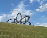 Ein skulpturales Kunstwerk auf einem Hügel, das an eine Achterbahn erinnert. Perfekt für spannende Ausflugsziele mit Kindern.