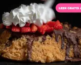 Pastel de bizcocho con chocolate derretido, fresas y una generosa porción de nata montada.