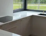 Nowoczesna kuchnia z blatem z **neolith spieki**. Złota bateria i czarny zlew przy dużym oknie.