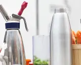 Espuma con sifón lista para crear texturas. Zanahorias frescas al lado, sugiriendo una receta innovadora.