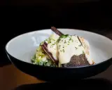 Pyszny lin w śmietanie, podany z puree ziemniaczanym i chrupiącym boczkiem. Danie posypane jest świeżą natką pietruszki.