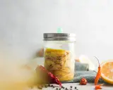 Ein Glas mit Ingwer fermentieren, daneben Zitronenscheiben und Chilis.