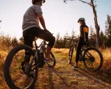 Dwie osoby na rowerach górskich odpoczywają na ścieżce wśród traw. Odkrywają malownicze trasy rowerowe Śląsk.