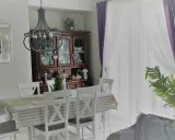 Przytulny styl prowansalski salon z drewnianą komodą, białymi krzesłami i stołem nakrytym w paski.